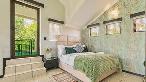 A bedroom with a bed, a nightstand, a window with blinds, a door leading to a balcony, and a patterned wall. - Zalari Luxe Loft B, Nature 1-Bed Loft, Paulshof (Sandton)