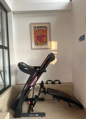 Une salle de sport à domicile équipée d’un tapis de course, de poids et d’une affiche accrochée au mur.