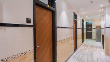A hotel corridor with wooden doors, tiled walls, and a marble floor.