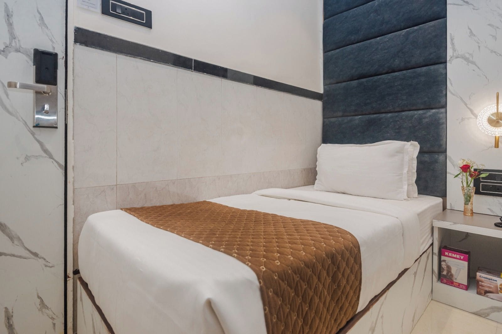 Ein Hotelzimmer mit einem Bett, einem Nachttisch mit Lampe und einer Wand-Klimaanlage.