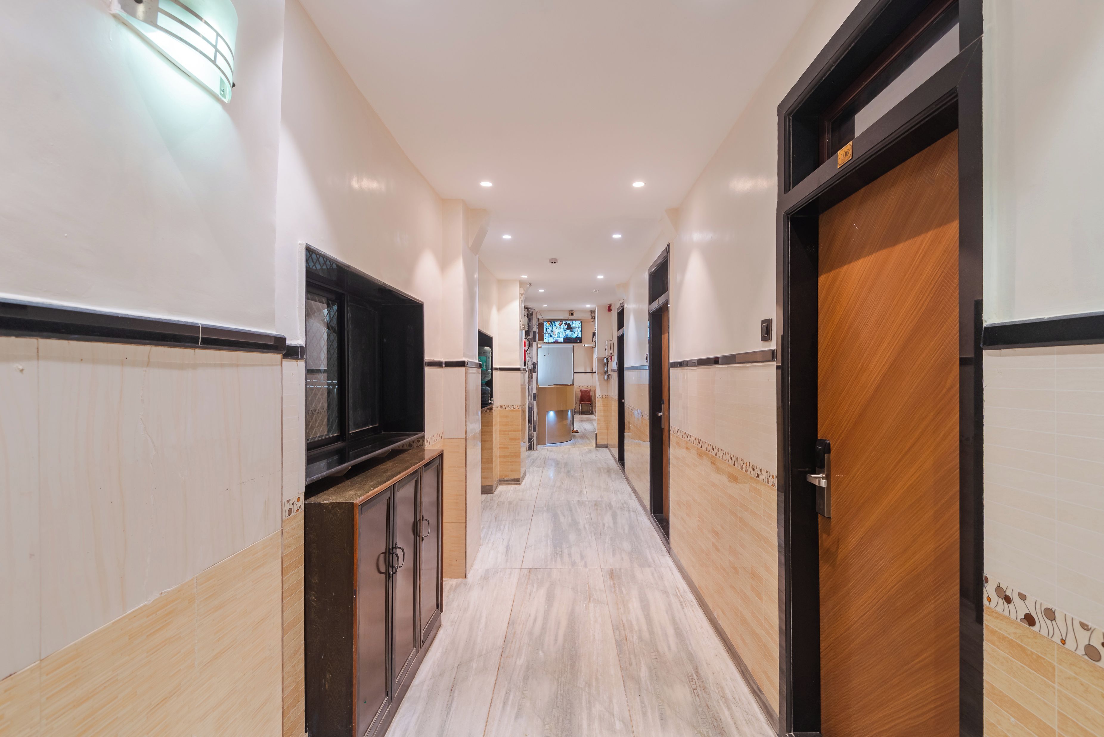 A hotel corridor with a TV, a reception desk, and a wooden door.