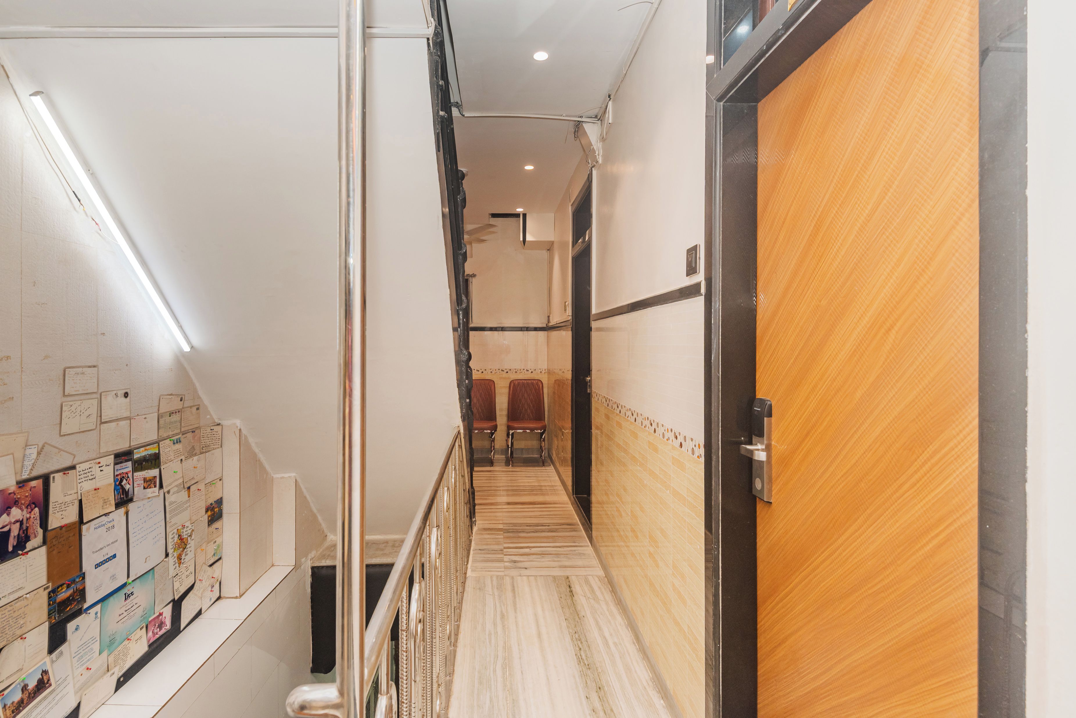 Un pasillo de hotel con una puerta de madera, una escalera y una pared decorada con notas e imágenes.