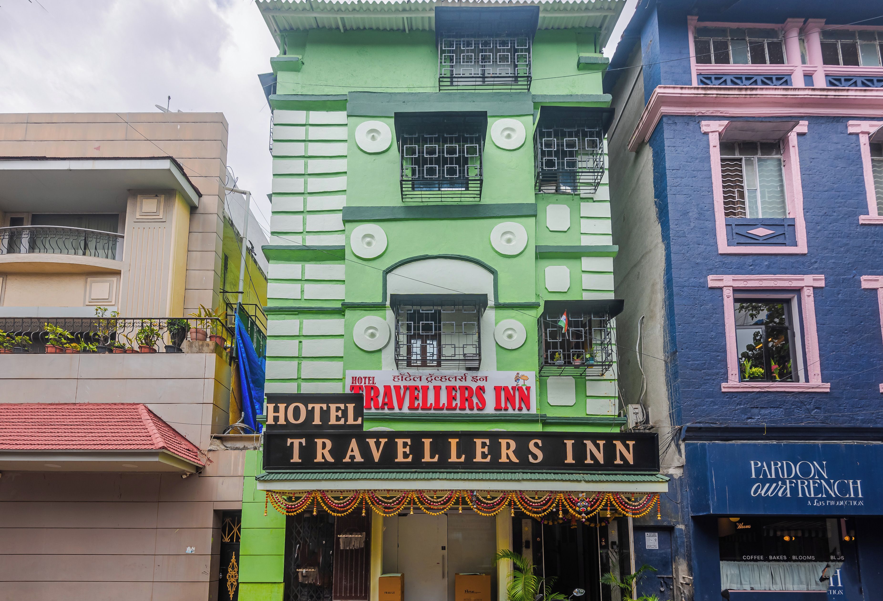 Um edifício de vários andares com uma placa indicando 'Hotel Travellers Inn', mostrando que se trata de um estabelecimento de hospedagem.