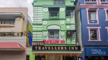 Um edifício de vários andares com uma placa indicando 'Hotel Travellers Inn', mostrando que se trata de um estabelecimento de hospedagem.