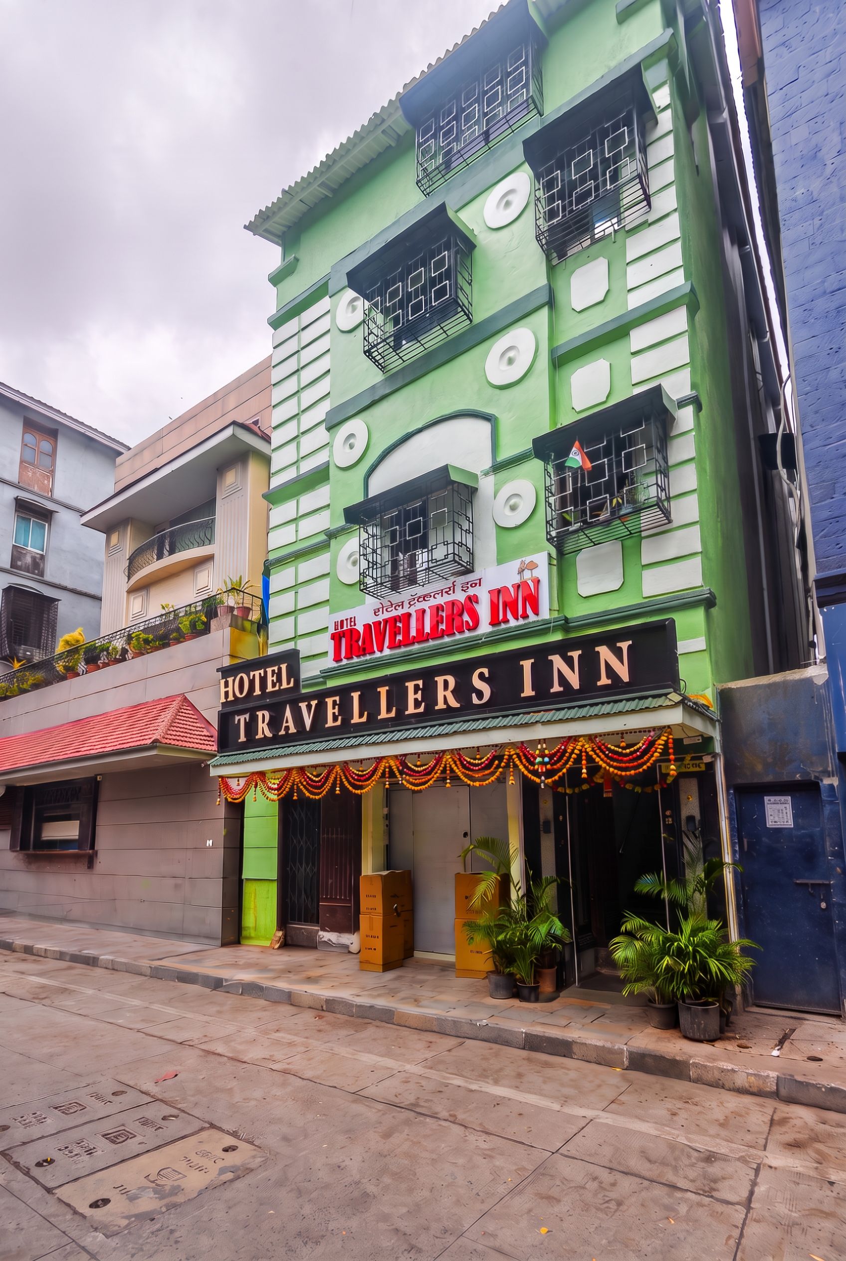 A green building with a sign for 'Hotel Travellers Inn' and balconies with railings.