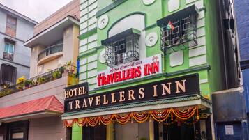 A green building with a sign for 'Hotel Travellers Inn' and balconies with railings.