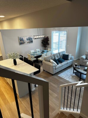 Una sala de estar moderna con comedor, una escalera y vistas al exterior.