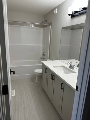 A modern bathroom with a shower, toilet, and vanity with a sink. - Luxury Home in Aspen (Calgary)
