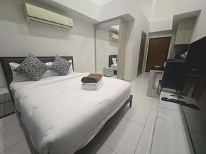 Een hotelkamer met een bed, een bureau, een stoel, een airconditioner en een spiegel.