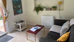 A living room with a sofa, a coffee table, a radiator, a bookshelf, and a painting. - La Clérynette awaits you in the heart of Château de Gaillard (Les Andelys)