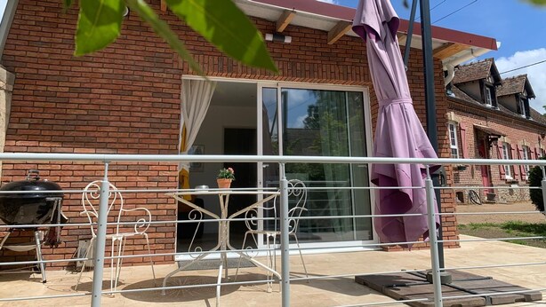 A brick house with a sliding glass door, a patio with a grill, and a purple umbrella. - La Clérynette awaits you in the heart of Château de Gaillard (Les Andelys)