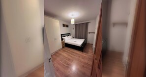 Een slaapkamer met een bed, nachtkastje en hanglamp.