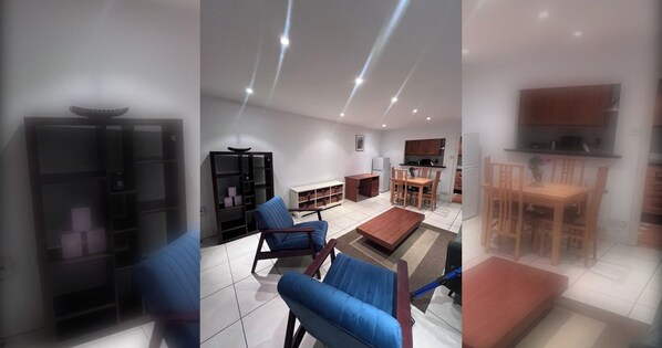 Een moderne woonkamer met een bank, stoelen, een salontafel, en een eethoek met een tafel en stoelen.