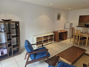 A modern living room with a sofa, a coffee table, a wooden cabinet, and a dining area with chairs and a table. - Bright 2 BDR APT on Charlotte Quay Dublin (Dublin)