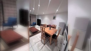 A modern living room with a dining area, a blue chair, a wooden table, and a white refrigerator. - Bright 2 BDR APT on Charlotte Quay Dublin (Dublin)
