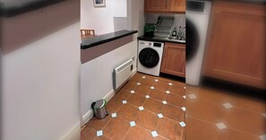 A compact kitchen with a washing machine, a sink, and a trash bin. - Bright 2 BDR APT on Charlotte Quay Dublin (Dublin)