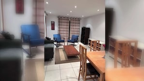 A living room with a sofa, two blue chairs, a wooden coffee table, a TV, and a bookshelf. - Bright 2 BDR APT on Charlotte Quay Dublin (Dublin)