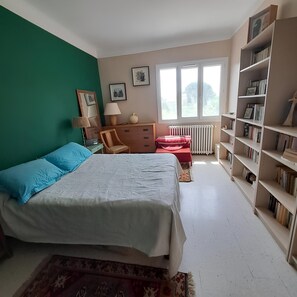A bedroom with a bed, a dresser, a bookshelf, a window, and a radiator. - Quiet, spacious double room in a Provencal villa in Pélissanne. (Pélissanne)