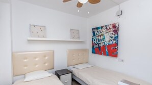 A bedroom with two beds, a small bedside table, a ceiling fan, and a motivational poster on the wall. - In the centre and near the beach (Fuengirola)