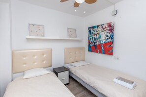 A bedroom with two beds, a small bedside table, a ceiling fan, and a motivational poster on the wall. - In the centre and near the beach (Fuengirola)