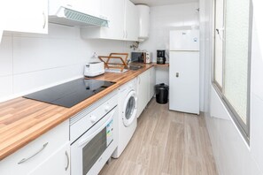 Eine kleine Küche mit Waschmaschine, Mikrowelle und Kaffeemaschine.