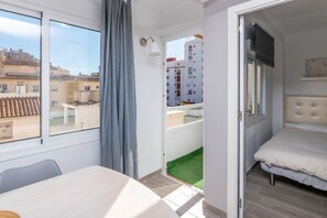 Ein Schlafzimmer mit einem Bett, einem Fenster und Blick auf Gebäude.
