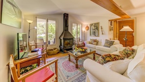 A cozy living room with a fireplace, white sofas, a coffee table, and a rug. - Beautiful House with Wi-Fi, Air Conditioning, and Pool in Exclusive Community (Cala de Sant Vicenç)