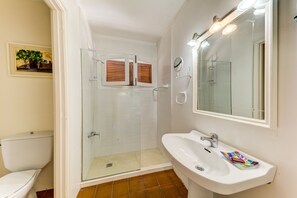 Een badkamer met een douchecabine van glas, een wit wastafelmeubel en een grote spiegel.