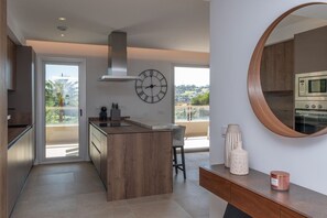 Eine moderne Küche mit Kochinsel, großem Fenster und Blick ins Freie.