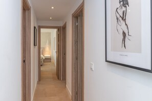 Ein Korridor mit Holztüren, einem gerahmten Kunstwerk an der Wand und einem Blick auf ein Badezimmer am Ende.