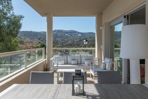 Ein Balkon mit einer Couch, einem Tisch und Stühlen mit Blick auf eine reizvolle Landschaft.