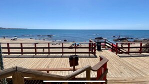 A wooden deck with a railing overlooking a beach with rocks and the sea. - Beachfront 2BR scenic sea views - Pool (Mijas)