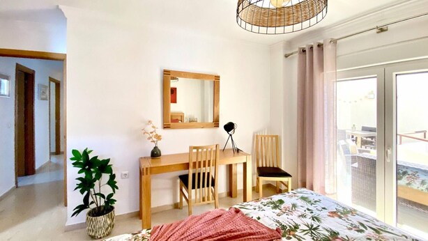 A bedroom with a bed, a desk, two chairs, a mirror, a potted plant, and a balcony view. - Beachfront 2BR scenic sea views - Pool (Mijas)