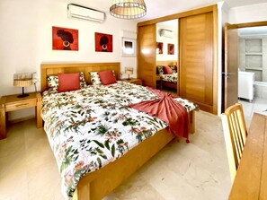 Ein Schlafzimmer mit Bett, Nachttisch, Stuhl, Spiegel und Kleiderschrank.