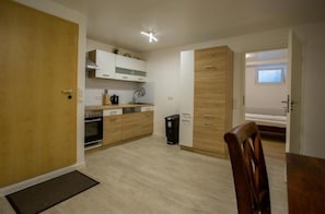 A compact kitchen with wooden cabinets, a built-in oven, and a small trash bin. - Business Apartment Kaiserslautern · Sleeps 2 · Full Kitchen · Living Room (Kaiserslautern)