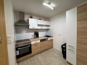 A compact kitchen with a stove, oven, sink, and white cabinets. - Business Apartment Kaiserslautern · Sleeps 2 · Full Kitchen · Living Room (Kaiserslautern)