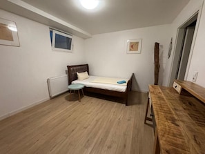 A room with a single bed, a small table, a radiator, and a window. - Business Apartment Kaiserslautern · Sleeps 2 · Full Kitchen · Living Room (Kaiserslautern)