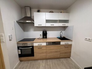 A compact kitchen with a stove, oven, dishwasher, and white cabinets. - Business Apartment Kaiserslautern · Sleeps 2 · Full Kitchen · Living Room (Kaiserslautern)