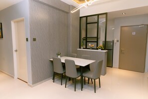 A modern dining area with a rectangular table and six chairs, a kitchen counter with a window, and a door with a no-smoking sign. - Trival Misty Cottage Homestay @ Sri Indah Sandakan (Sandakan)