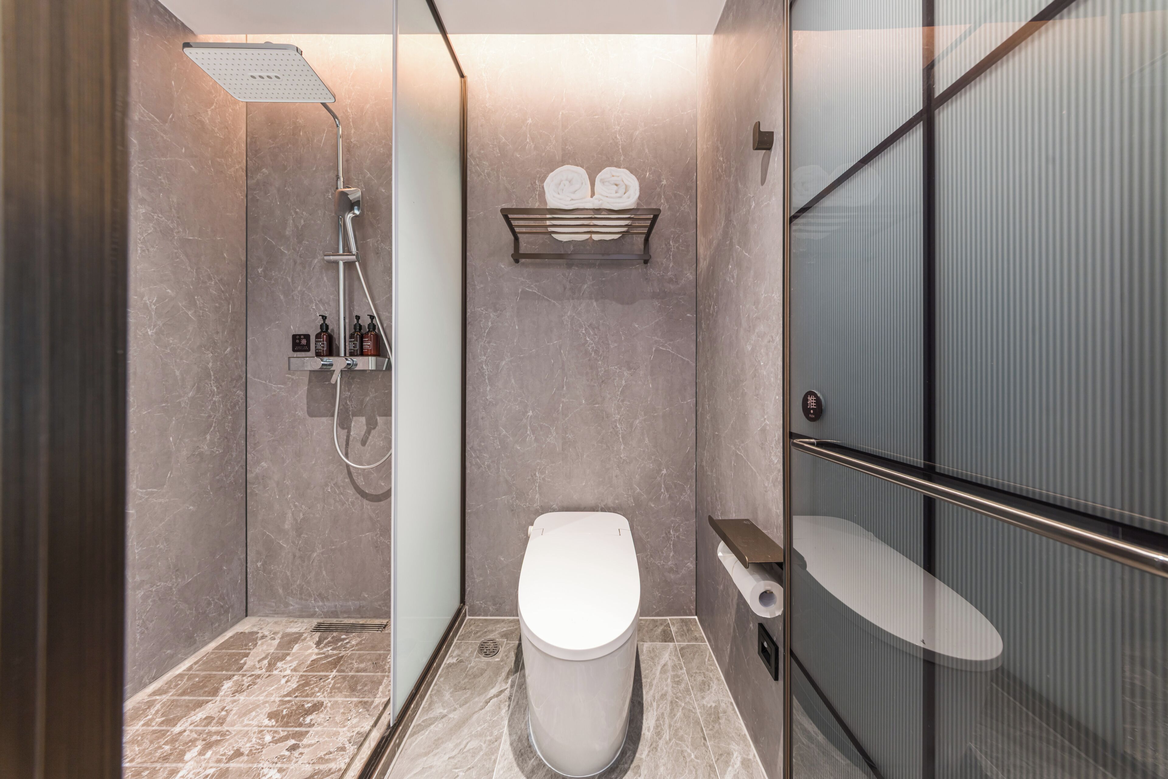 A modern bathroom with a shower, toilet, and glass enclosure.