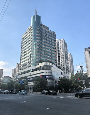 A multi-story hotel with a distinctive curved facade, located at a city intersection. - Jinglai Hotel (Chenghuang Xintiandi Lujiabang Metro) (Shanghai)