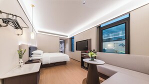 A modern hotel room with a bed, a sofa, a small table with flowers, a TV, and a window. - Jinglai Hotel Shanghai Yuyuan Xintiandi Lujiabang Road Metro (Shanghai)