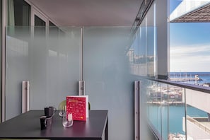 Ein Balkon mit Blick auf das Meer, ein Tisch mit einem Buch und einem Glas.