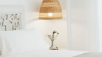 Een slaapkamer met een bed, een nachtkastje met een bloevas en een wandlamp.