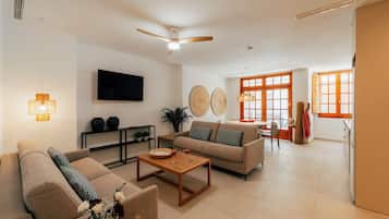 A spacious living room with a ceiling fan, a flat-screen TV, and a dining area with a table and chairs.