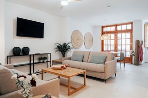 Una sala de estar con sofá, mesa de centro, televisor y objetos decorativos.