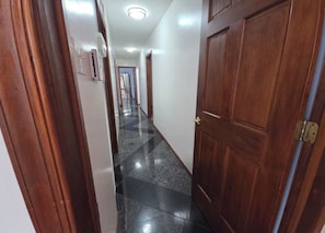 A hallway with a wooden door, a white wall, and a tiled floor. - Chelsea Chalet - 4BR, Comfortable Stay Near It All (Atlantic City)