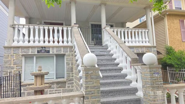 A two-story house with a stone facade, a covered porch with white balustrades, and a stone staircase leading to the second floor. - Chelsea Chalet - 4BR, Comfortable Stay Near It All (Atlantic City)
