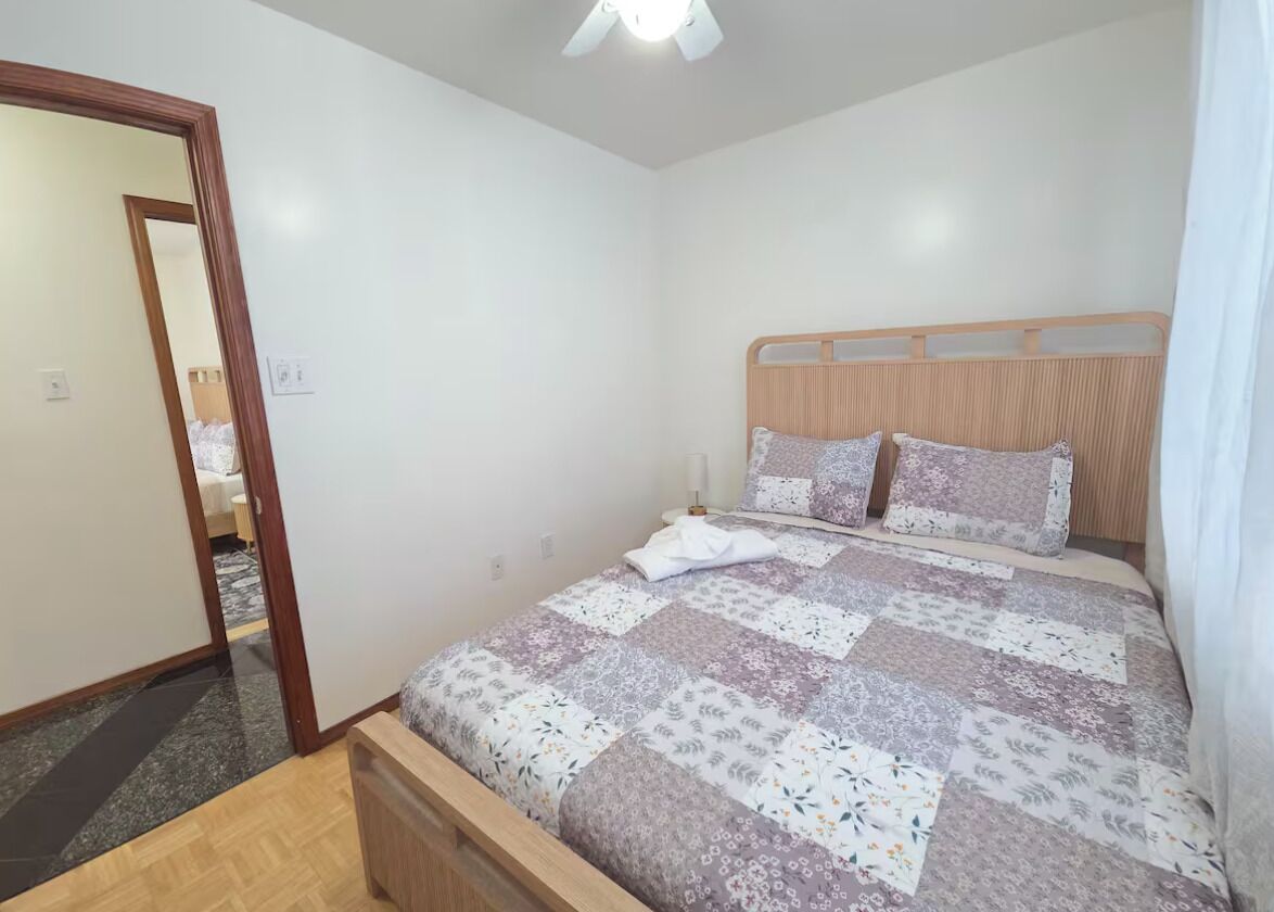 Un dormitorio con una cama de madera, un espejo y una puerta que da a otra habitación.