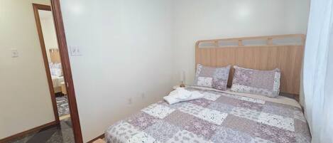 Un dormitorio con una cama de madera, un espejo y una puerta que da a otra habitación.